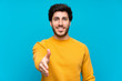 © luismolinero - Handsome over isolated blue wall shaking hands for closing a good deal