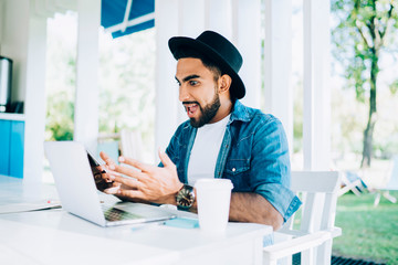 Emotional hipster guy shocked with received advertising message with promo code - discount and promotion in favourite web store, astonished man reading news in group chat from work feeling shocked
