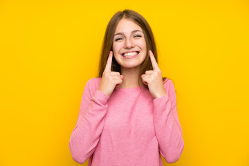 Wall Mural - Young woman with long hair over isolated yellow wall smiling with a happy and pleasant expression