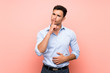 © luismolinero - Handsome man over pink background showing a sign of silence gesture putting finger in mouth