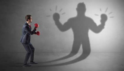 Canvas Print - Businessman trying to fight with his unarmed shadow
