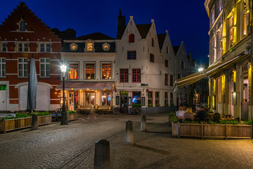 Wall Mural - Old street with tables of cafe in Bruges (Brugge), Belgium. Night cityscape of Bruges. Typical architecture of Bruges