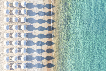 Wall Mural - View from above, stunning aerial view of an amazing empty white beach with white beach umbrellas and turquoise clear water during sunset. Mediterranean sea, Sardinia, Italy.