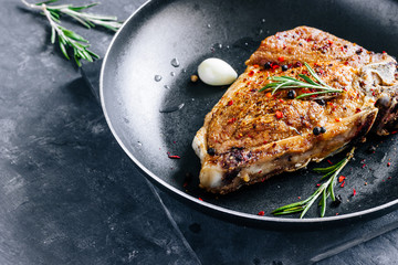 Poster - Piece of fried meat with rosemary and garlic in a pan close up