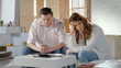 © motortion - Couple sitting depressed near money calculator, conflict over low family budget