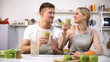 Positive couple toasting fresh green smoothie, healthy lifestyle, antioxidant
