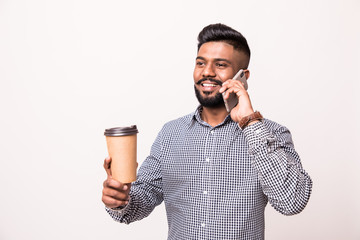 Canvas Print - Handsome indian man holding coffee cup and talking on the phone isolated on white background