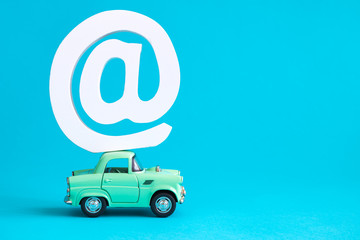 Email symbol on the top of car toy roof abstract isolated on blue.