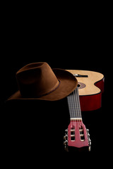 Fototapete - American culture, folk song and country muisc concept theme with a cowboy hat and an acoustic guitar isolated on black background with dramatic lighting