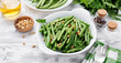 Sauteed green beans with pine nuts in a baking dish, healthy side dish.