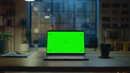 Wall Mural - mock-up green screen laptop standing on the desk in the modern creative office. in the background wa