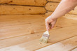 © Lyubov - Applying varnish paint on a wooden surface. Man hand with a brush closeup. Painting wood wall and  floor.