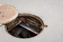 Closeup Of An Open Manhole With A Lid On The Asphalt Road. Danger For People. Underground Repair.