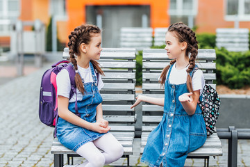 Wall Mural - Two beautiful  happy girlfriends girls go to school. Waiting lesson. Back to school speak and spend time together.