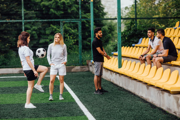 Two,sportive  female soccer players on the field  with boys.