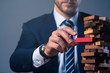 © whyframeshot - caucasian businessman suit hand hold wooden tower stack block organize and strategy ideas concept