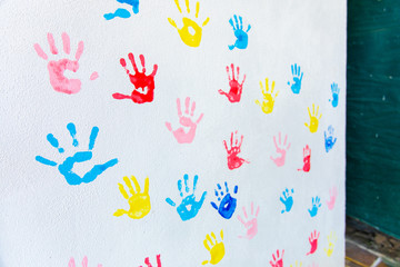 Colorful hand prints of hands isolated on white wall background. Children's handprints on school wall