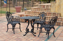 Wrought Iron Furniture Dining Table And Chairs Kept Outside On A Tiled Floor At A Cafe. Tiled Staircase Is Also Visible In The Background On A Summer Evening 