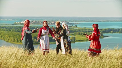 Wall Mural - People in traditional russian clothes dancing on the field by the music