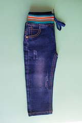 Children's blue jeans for boys on green background.