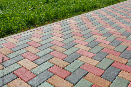 Cuadros en Lienzo Colorful cobblestone road pavement and lawn divided by a concrete curb