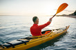 © yossarian6 - Rear view of senior man enjoy paddling kayak on the sunset sea