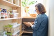 © Valerii Honcharuk - Interior of wooden pantry with products for cooking. Adult woman taking kitchenware and food from the shelves