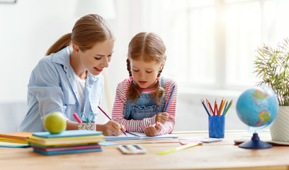 Wall Mural - mother and child daughter doing homework writing and reading at home.