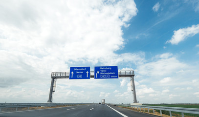 Wall Mural - Koln, Germany - Aug 15, 2018: Two large autobahn blue road signs with Dusseldorf, Neuss, Heinsberg, Venlo and Monchengladbach direction