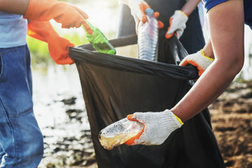 volunteer woman picking up garbage plastic for cleaning at river park