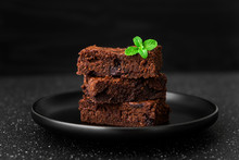 Dark Chocolate And Cocoa Brownie Fudge Cakes Dessert With Mint Against Black And Grey Stone Background