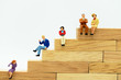 Miniature people: Business people sitting on wooden box .