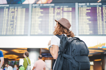 happy young girl traveler at the airport on the background of the departures board