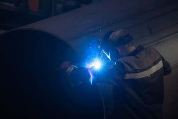 Wall Mural - Worker in protective mask welding pipe in factory