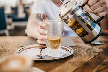 pouring green tea into a glass cup in a cafe