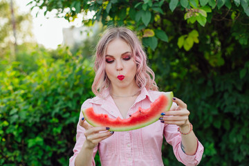 Beautiful young woman with pink hair enjoying watermelon