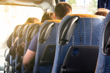 A row of comfortable bus seats and the backs of passengers in them. Travel and tourist trip to another country. Bus tours abroad. Modern scheduled buses, transportation between cities and countries.