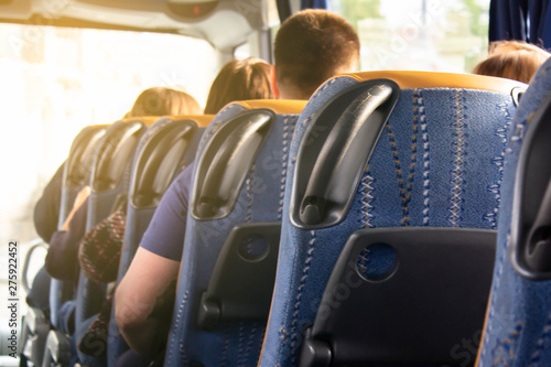 A row of comfortable bus seats and the backs of passengers in them. Travel and tourist trip to another country. Bus tours abroad. Modern scheduled buses, transportation between cities and countries.