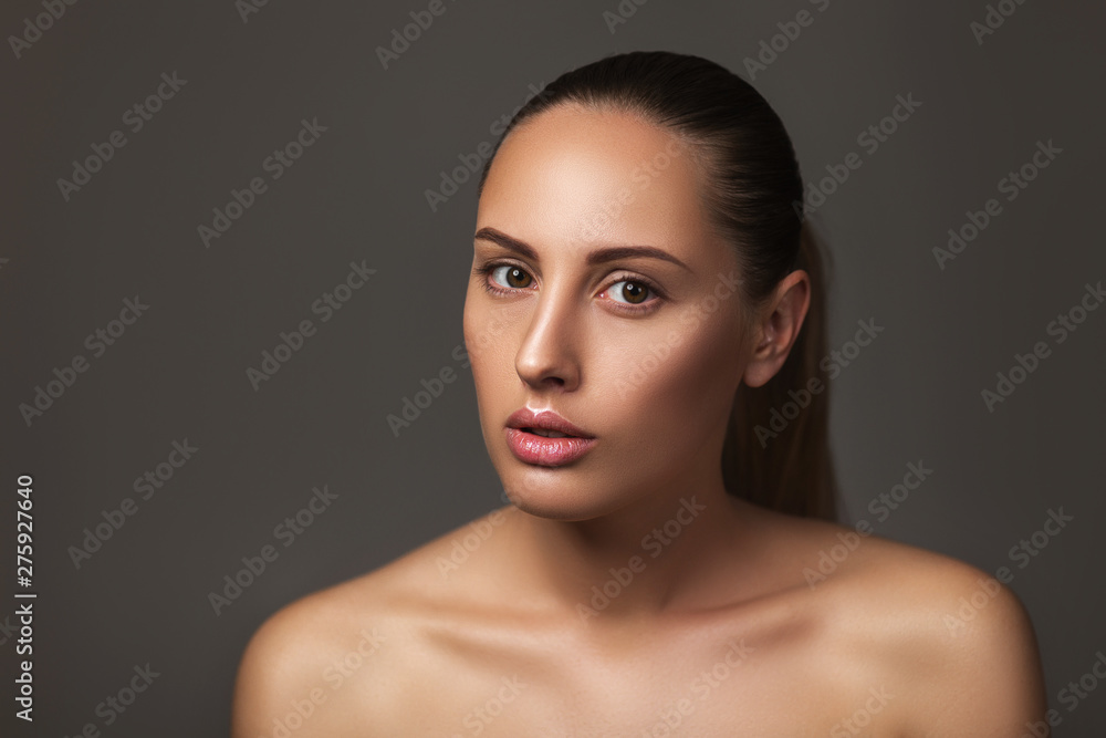 Beauty portrait of female face with natural perfect skin. model with light nude make-up on dark