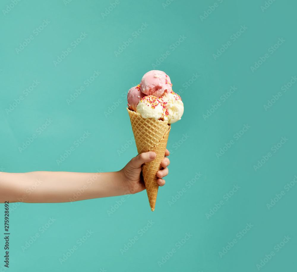 Baby kid hand holding big ice-cream in waffles cone on blue - obrazy, fototapety, plakaty 