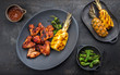 Exotically barbecue chicken wings with hot chili sauce, jalapeno and pineapple as top view on a cast iron plate