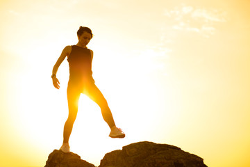 Young Beautiful Woman Walking on the Rocks in the Mountains at Summer Sunset. Travel and Adventure Concept.