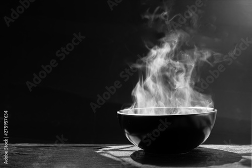 Cuadros en Lienzo Steam of hot soup with smoke wood bowl on dark background