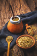Yerba mate in calabash with bombilla and dry herb in wooden bowl on wooden background