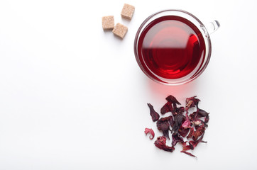 Top view of Hibiscus Tea cup with petals and sugar cubes aside on white background