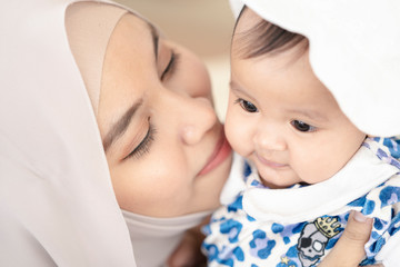 Wall Mural - Asian Muslim mother woman kissing and hugging a  baby in her arms. family concept.