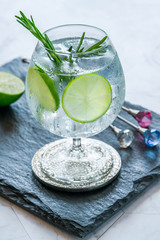 Gin and tonic cocktail with lime and rosemary - refreshing summer alkoholic drink