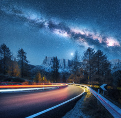 Wall Mural - milky way over mountain road. blurred car headlights on winding road in autumn. colorful night lands