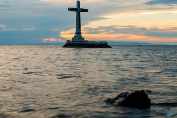 Wall Mural - Sunset behind a large cross in the ocean on a tropical island (Sunken Cemetery, Camiguin, Philippines)