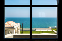 Inside View Through The Window With Frame In The Background Blur Backyard With Green Grass And Sea Horizon With Blue Water And Sky.